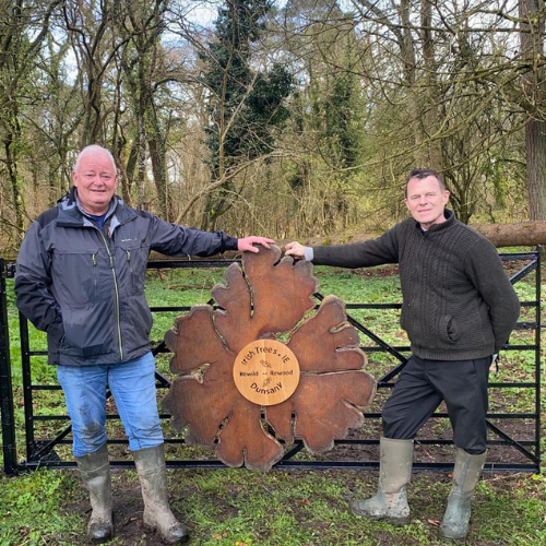 Bob and John of Irish trees at gate with irish Trees and Dunsany sign in wood on black gate with trees in background