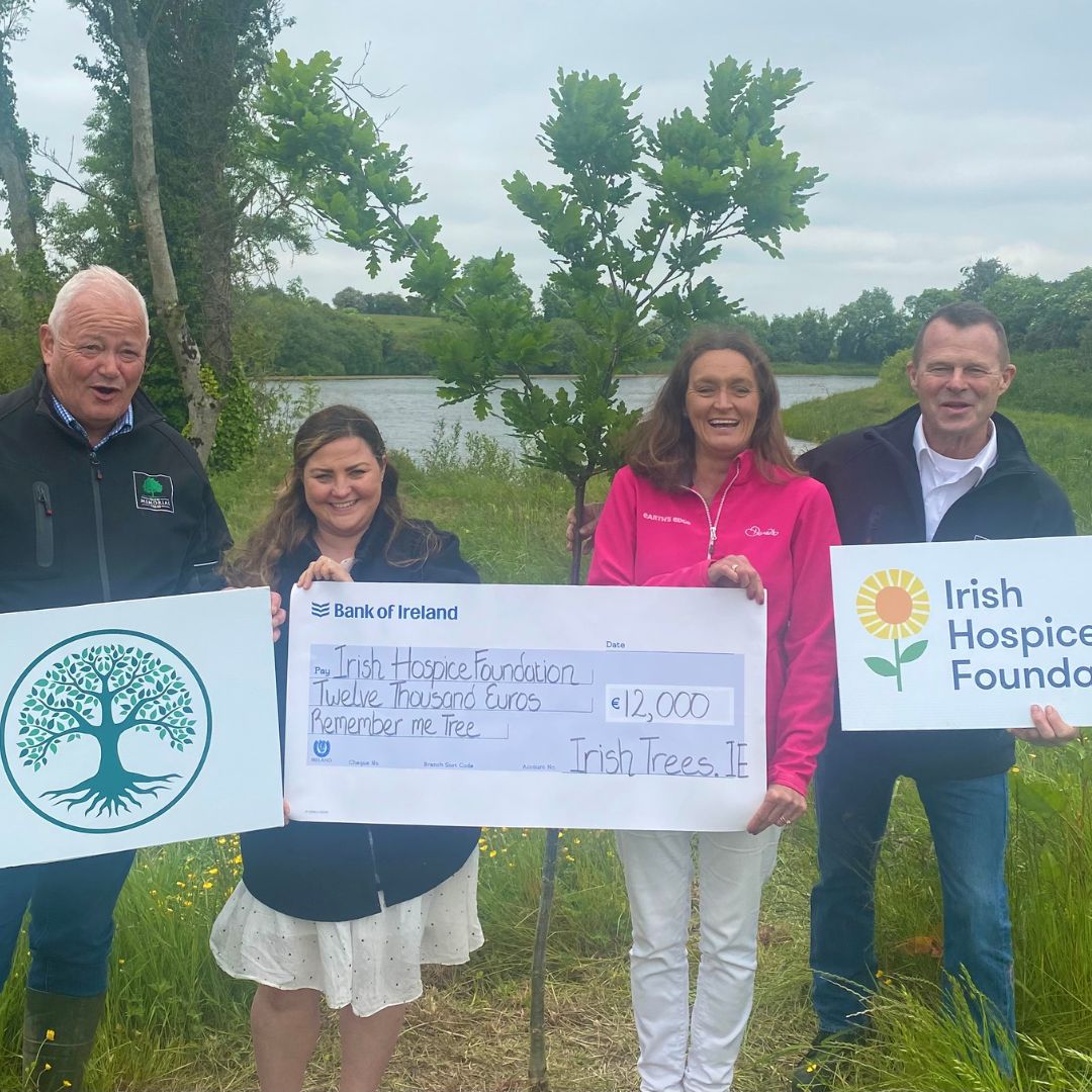 4 people - 2 men 2 women hold a cheque for €12,000 in front of the lake at irishtrees.ie in support of the Irish Hospice foundation
