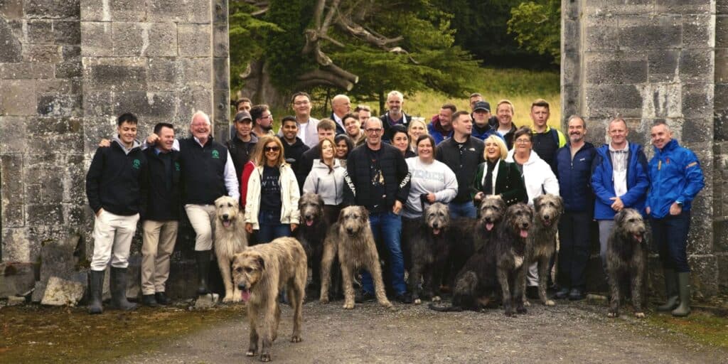 group of people at Dunsany laughing at the gate with wolfhounds